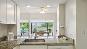 A modern kitchen with a granite countertop, white cabinetry, and a built-in dishwasher.