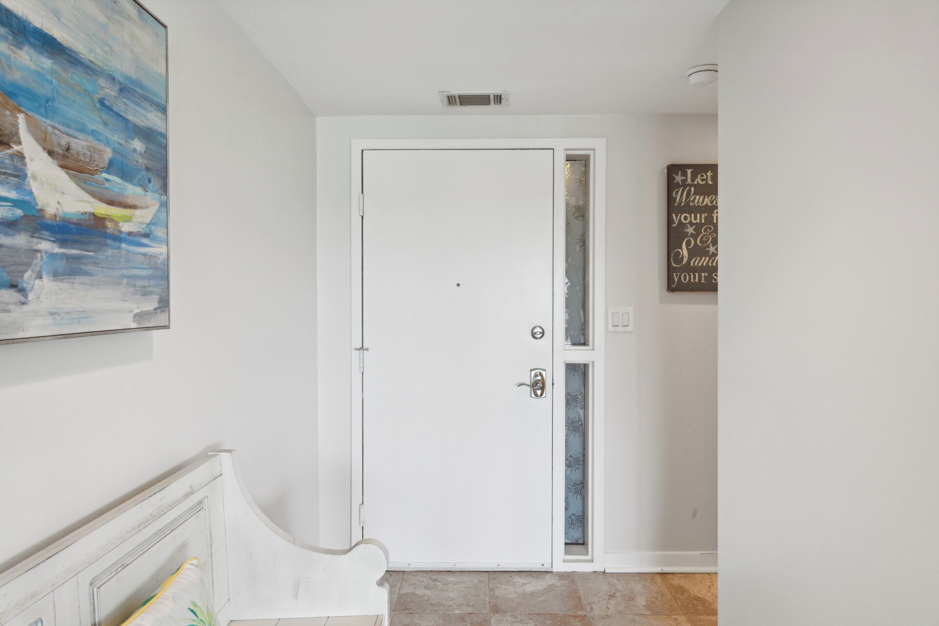 A white door with a small window, a wall-mounted sign, and a painting above it.