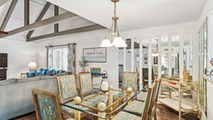 A dining area with a glass table and patterned chairs, a sofa, and a chandelier. - Pet Friendly with Scenic Views, Close to Beach! (Hilton Head Island)