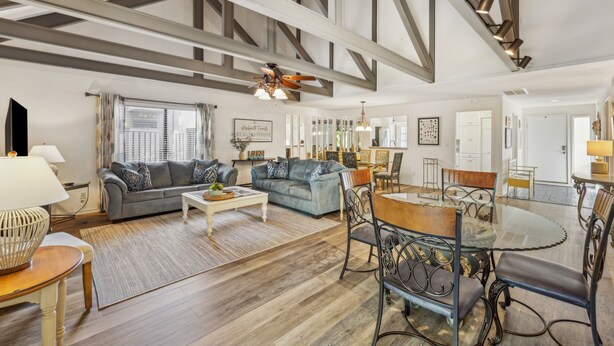 A spacious living room with a high ceiling, a dining area with a glass table, and a kitchen in the background. - Pet Friendly with Scenic Views, Close to Beach! (Hilton Head Island)