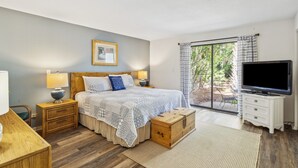 A bedroom with a bed, bedside tables, a TV, and a view of the outdoors. - Pet Friendly with Scenic Views, Close to Beach! (Hilton Head Island)
