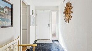 A hallway with a wooden bench, a door, and a wall-mounted decorative piece. - Pet Friendly with Scenic Views, Close to Beach! (Hilton Head Island)