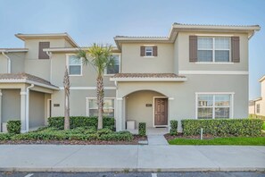 A two-story residential building with a beige facade, brown shutters, and a central entrance with a door. - Lake View and Mickey Room! Stunning Home! #5sl851 (Kissimmee)