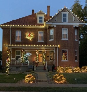 A two-story brick house with a porch decorated with Christmas lights and wreaths. - Zinfandel Room - Old Vine (Hermann)