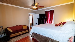 Une chambre à coucher avec un lit, un canapé, un ventilateur de plafond et un téléviseur.