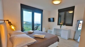 Une chambre à coucher avec un lit, un bureau, une télévision et une vue sur la campagne.