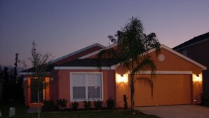 Una casa residencial con garaje, césped cuidado y una palmera.