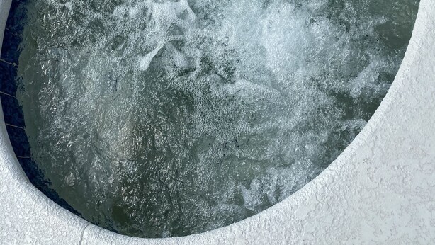 Una fuente circular con un borde blanco texturizado, rodeada por un borde de hormigón.