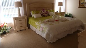 Un dormitorio ordenado con cama, mesitas de noche y un velador.