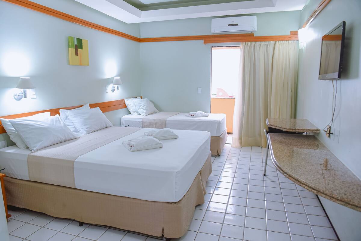 A hotel room with two beds, a bathroom, and a small kitchenette.