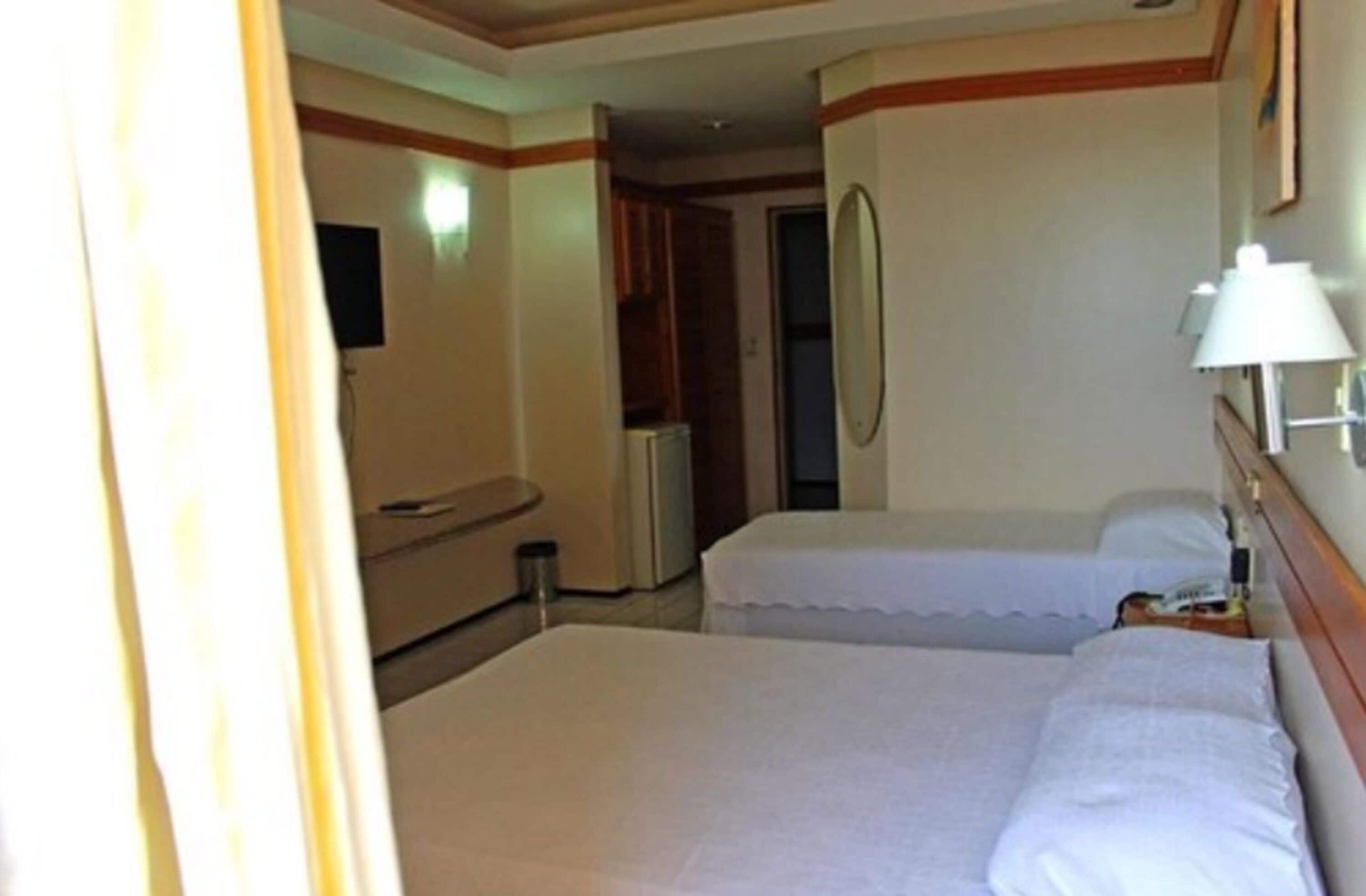 Hotellihuone, jossa on kaksi sänkyä, kylpyhuone ja pieni oleskelualue.