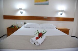 Una habitación de hotel con una cama grande, dos lámparas de noche, un cabecero de madera y una pequeña mesa con una planta.