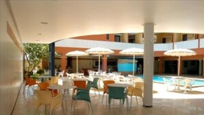 A spacious outdoor area with multiple tables and chairs, umbrellas, and a pool. - Hotel Praia Ponta D'areia (São Luís)