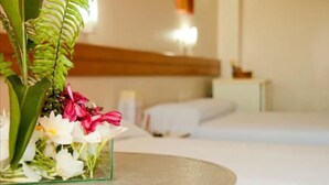 A hotel room with a bed, a bedside table, and a glass vase with flowers. - Hotel Praia Ponta D'areia (São Luís)
