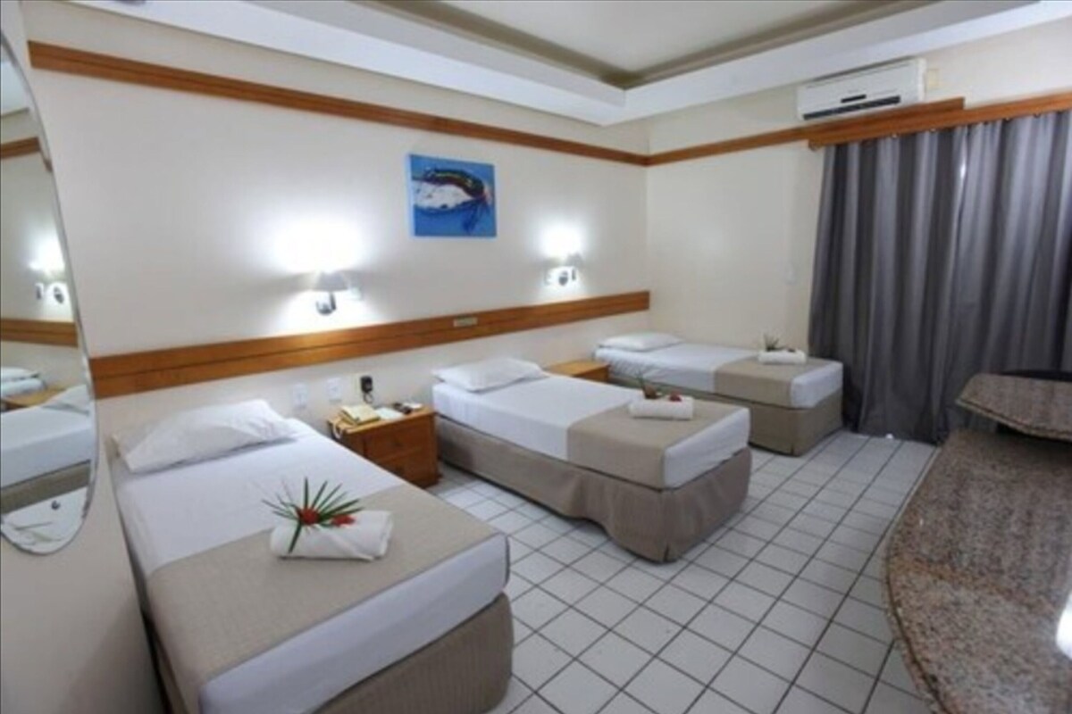 A hotel room with two beds, a nightstand, a desk, and a bathroom mirror.