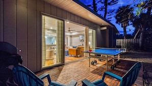 Una casa moderna con mesa de ping pong, mobiliario exterior y una zona de patio.