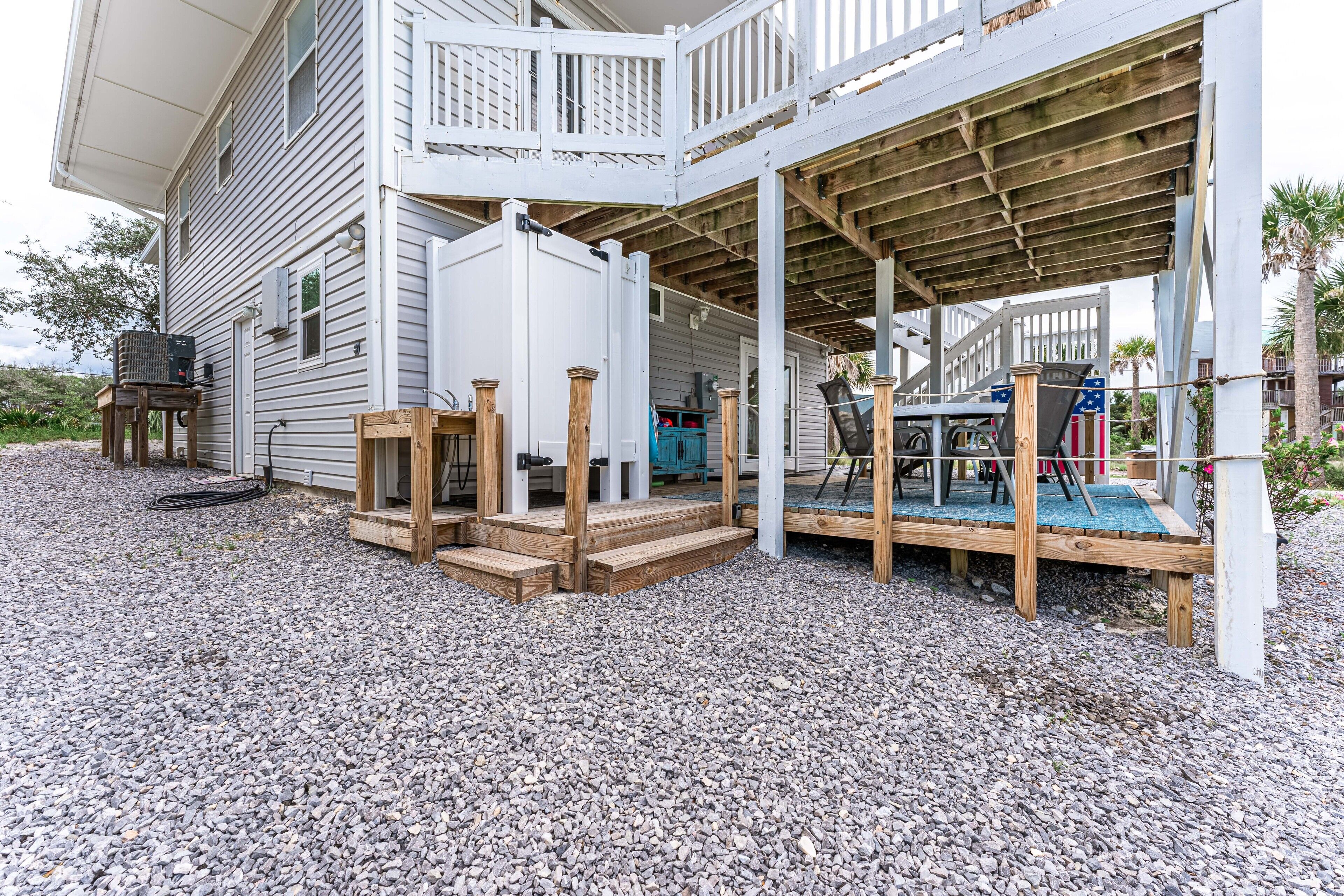 Un espace extérieur abrité, avec des marches menant à une terrasse en bois, un barbecue et un meuble bleu.