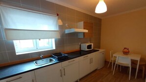 A compact kitchen with a sink, a microwave, and a small dining table with chairs. - Alojamento 2 Dos Santos (Pinhão)