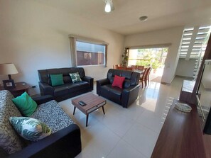 Uma sala de estar com dois sofás, uma mesa de centro e um espaço de jantar com cadeiras e mesa.
