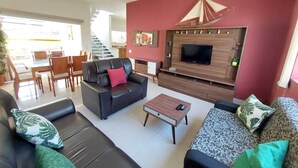 A living room with a sofa, a coffee table, and a TV mounted on a wooden wall.
