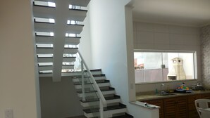 A modern kitchen with a built-in oven, a window with a view of the outside, and a staircase with glass railings.