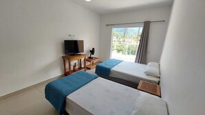 A hotel room with two beds, a TV, a ceiling fan, and a window with curtains.