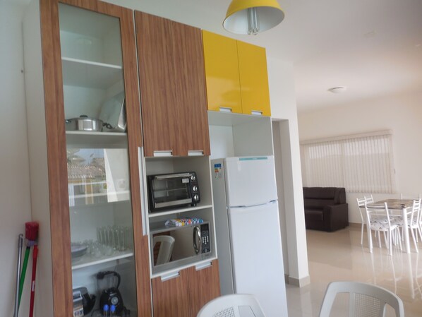 Una cocina equipada con microondas, tostadora y refrigerador. Hay una zona de comedor con mesa y sillas.