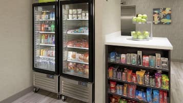 Un puesto de aperitivos con una variedad de productos envaselados y una sección refrigerada con bebidas y productos lácteos.