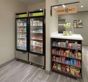 A snack kiosk with a variety of packaged snacks and a refrigerated section with beverages and dairy products. - Home2 Suites by Hilton Owasso (Owasso)