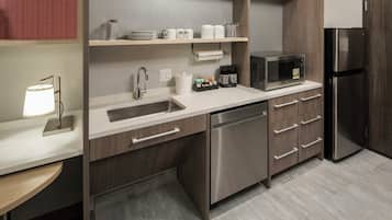 A modern kitchen with a stainless steel sink, dishwasher, microwave, and refrigerator.