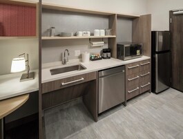 Una cocina moderna con pileta de acero inoxidable, lavavajillas, microondas y refrigerador.