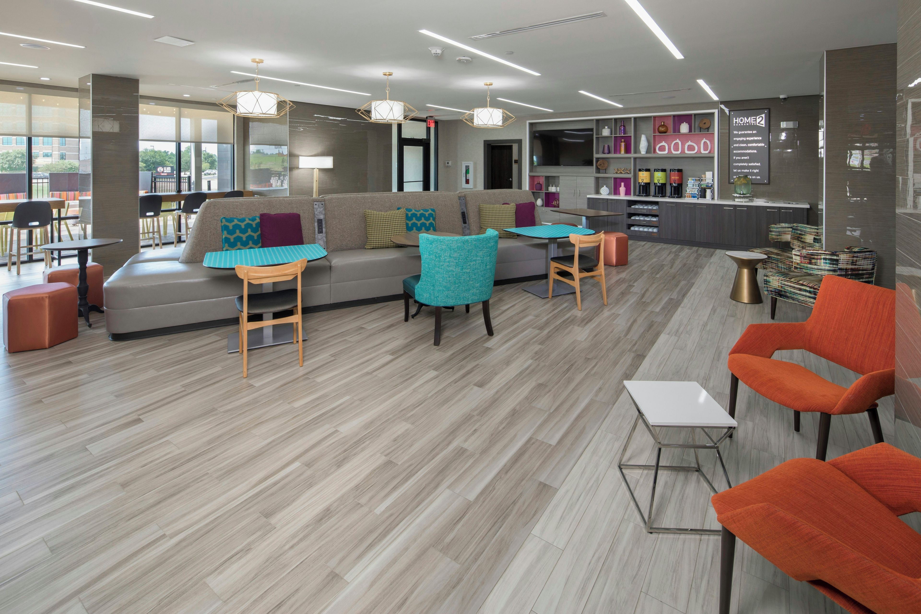 A modern lounge area with a sofa, chairs, a small table, and a bar area with shelves.