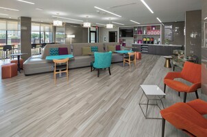 Un área de estar moderna con un sofá, sillones, una mesita y una zona de bar con estanterías.