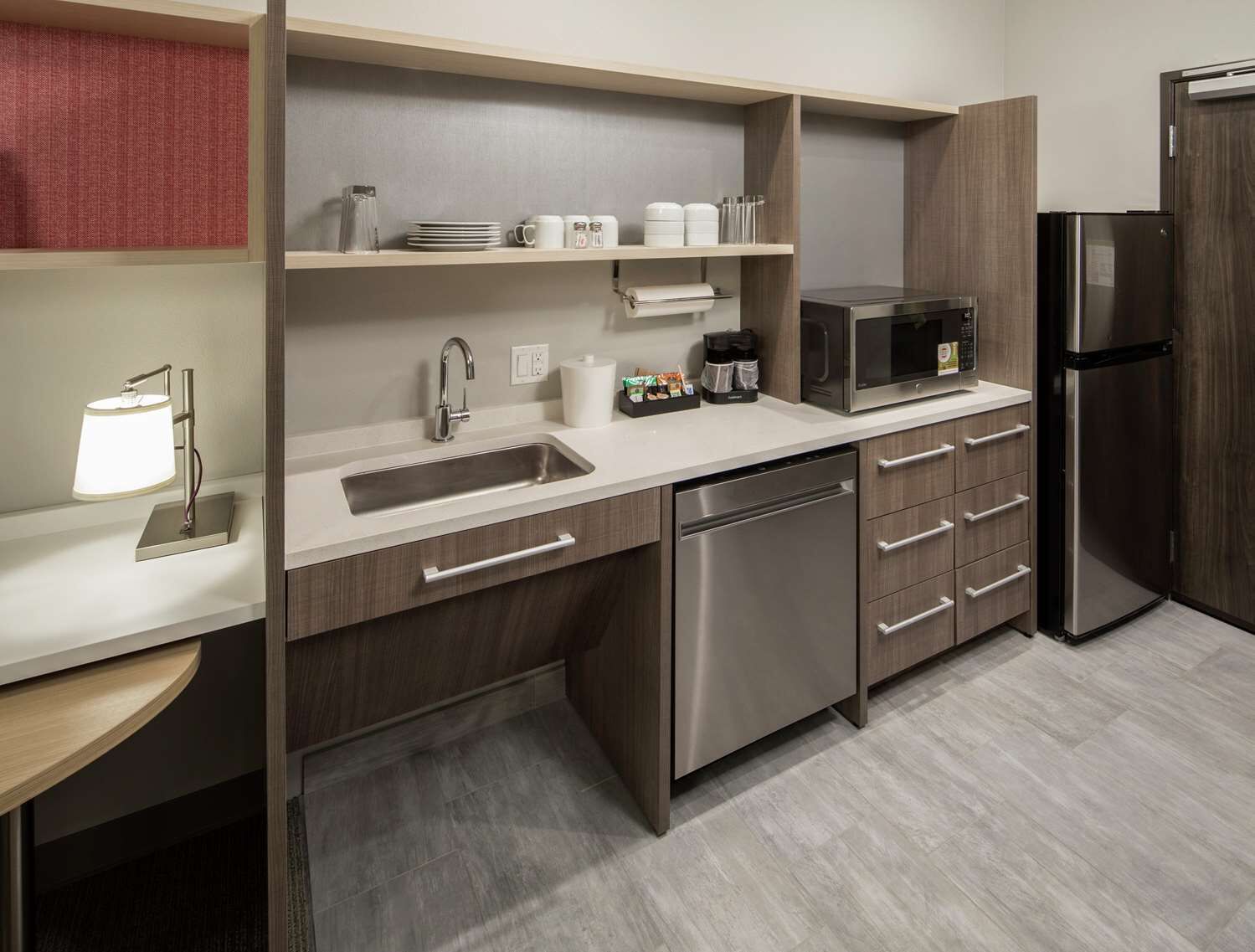 A modern kitchen with a stainless steel sink, dishwasher, microwave, and refrigerator.