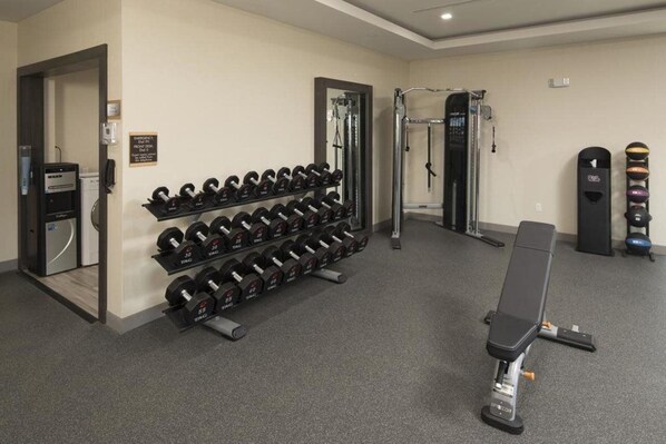 A gym with weight racks, a bench, and a squat rack. - Home2 Suites by Hilton Owasso (Owasso)