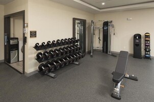 Un gimnasio con jaulas de pesas, una banca y una estructura para sentadillas.