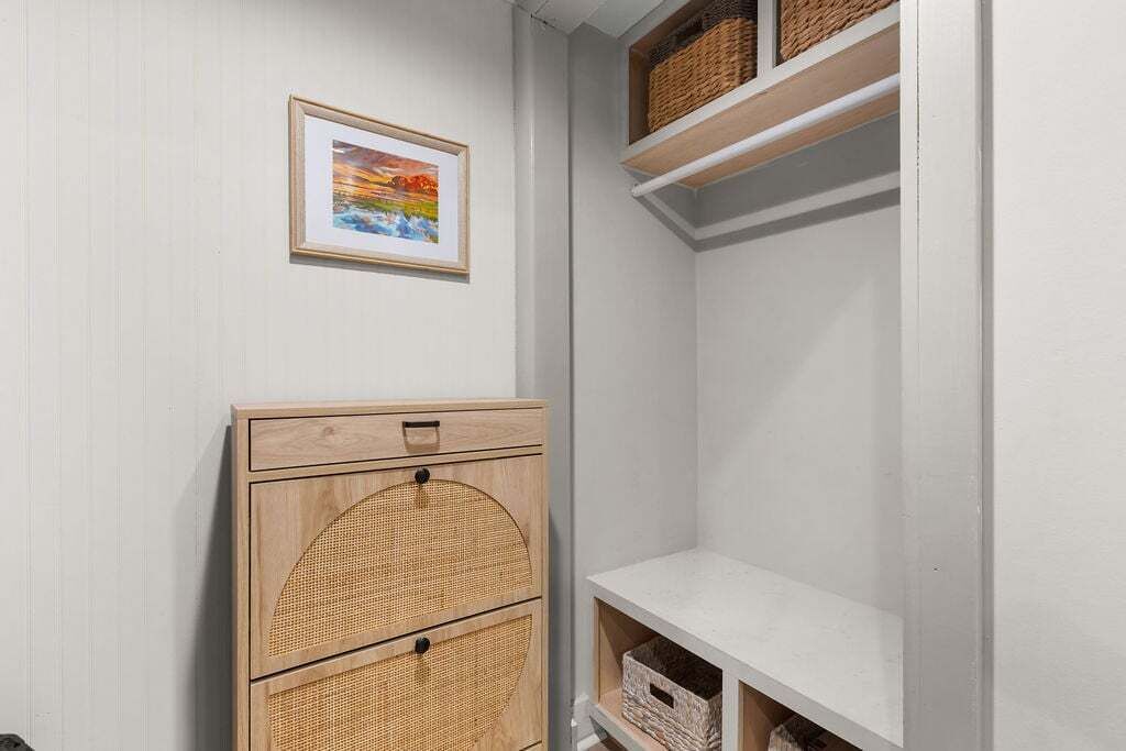 Une pièce avec un meuble en bois doté de tiroirs, un tableau encadré accroché au mur et des étagères avec des paniers.