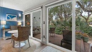 A room with a sliding glass door leading to an outdoor patio with wicker furniture and potted plants. - 1 BR/1.5 BA Villa! Amenity access included. NO pets (Seabrook Island)