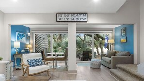 A modern living room with a dining area, a large window, and a view of the outdoors. - 1 BR/1.5 BA Villa! Amenity access included. NO pets (Seabrook Island)