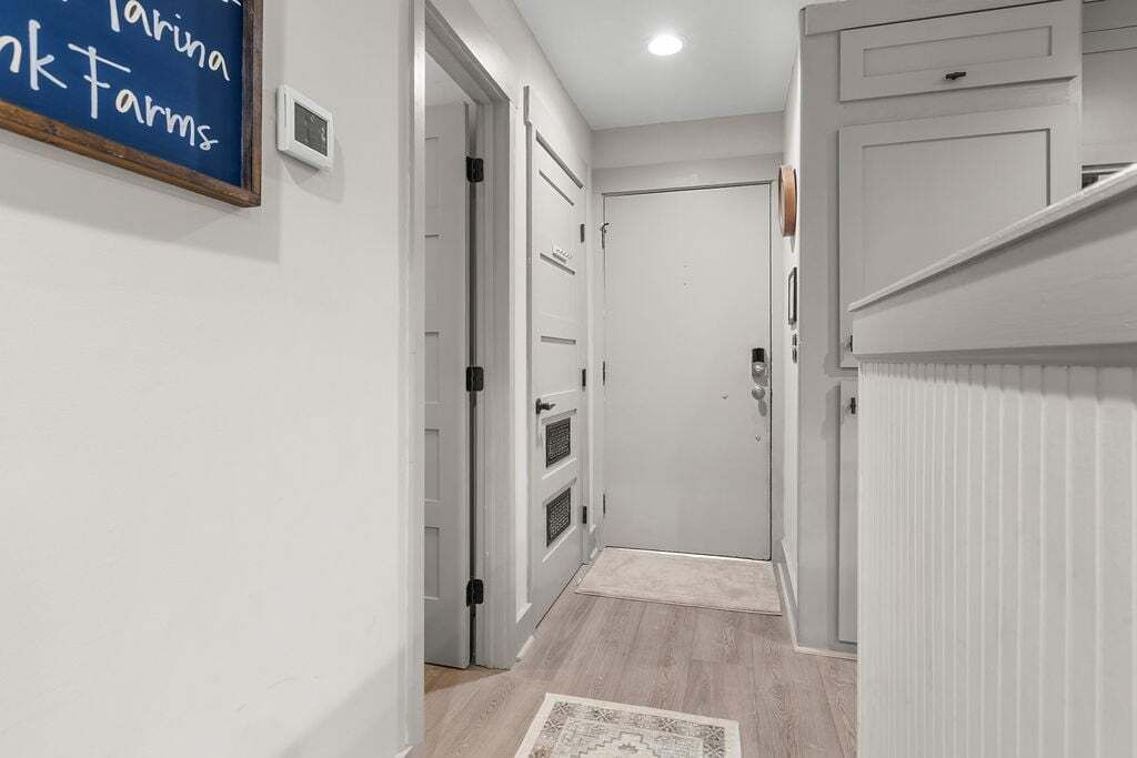 A narrow hallway with white doors, a small rug, and a sign on the wall.