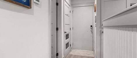 A narrow hallway with white doors, a small rug, and a sign on the wall.