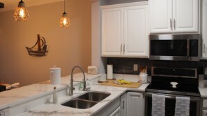 Una cocina moderna con armarios blancos, electrodomésticos de acero inoxidable e iluminación colgante.