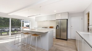 A modern kitchen with a large island, stainless steel appliances, and a view of the outdoors. - A Family home made for beach holidays & sunshine (PORT FAIRY)