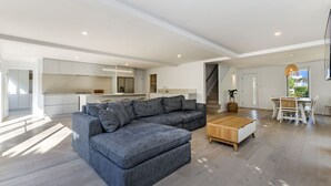 A spacious living area with a grey sectional sofa, a wooden coffee table, and a dining set. - A Family home made for beach holidays & sunshine (PORT FAIRY)