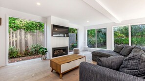 Una sala de estar moderna con chimenea, ventanas amplias y vista al jardín.
