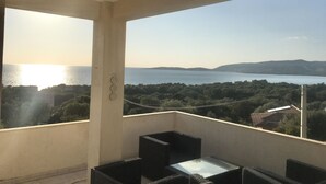 A balcony with a view of a body of water and distant hills.