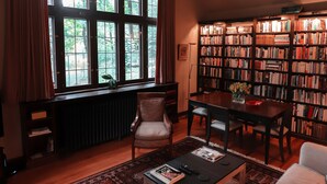 A cozy living room with a large window, a bookshelf, a coffee table, and a sofa.