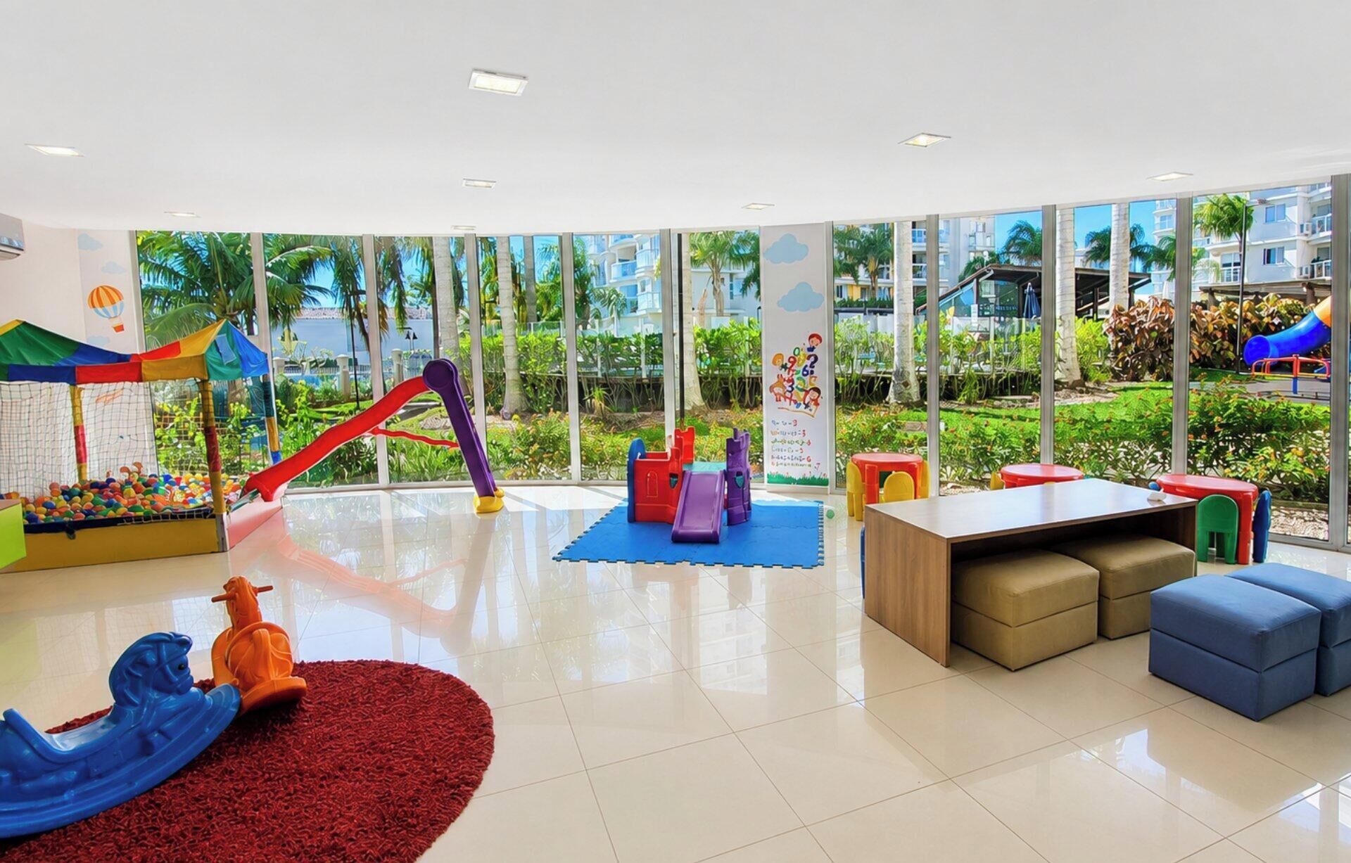 Uma área de recreação infantil com piscina de bolinhas, escorregadores e mobiliário macio.