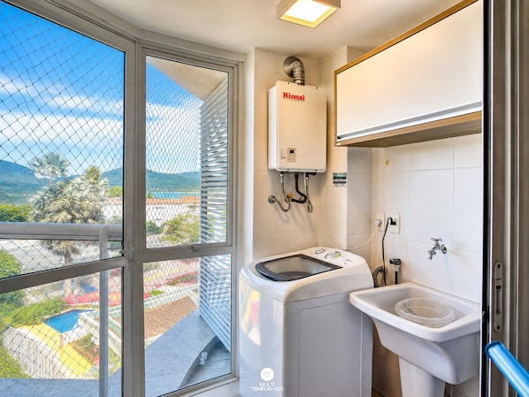 Un baño con un calentador de agua Rinnai, una lavadora y un lavabo con un bote de basura.