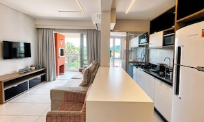 Een moderne keuken met een flatscreen televisie, een zithoek met een bank en uitzicht op de omgeving.